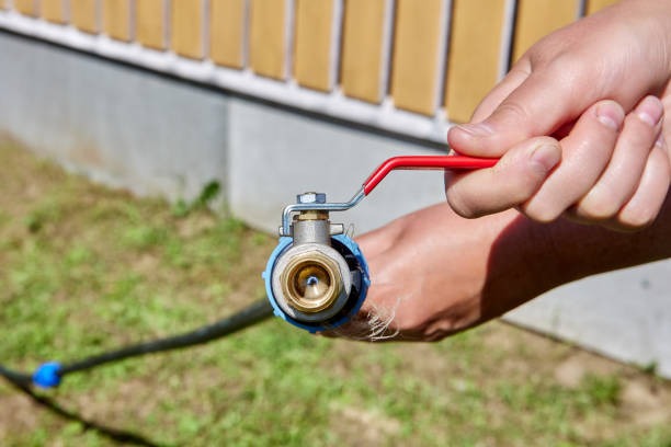 A solid brass ball valve connected to copper pipes on a residential water heater