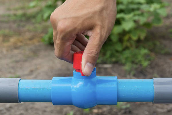 A technician inspecting a PVC valve in a pipeline for leaks or damage