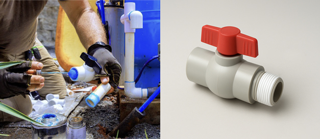 A person applying purple PVC primer to the end of a pipe before connecting a valve
