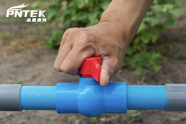 A maintenance worker inspecting a row of PVC ball valves with a checklist