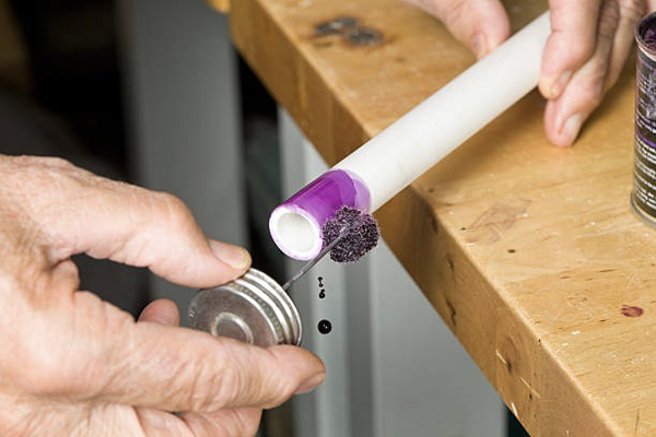 A professional correctly applying PVC cement to a pipe before installing a Pntek ball valve