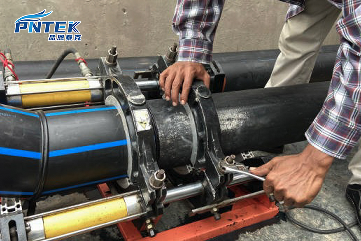 A technician using a socket fusion welding machine to join a grey PP pipe and fitting