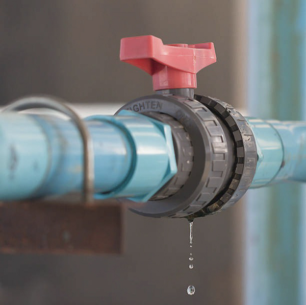 A PVC ball valve with a small drip coming from the handle stem