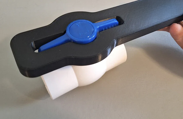 A person using channel-lock pliers correctly on a PVC valve handle near its base