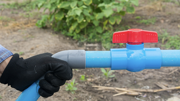 A white PVC ball valve with a red handle in an open position