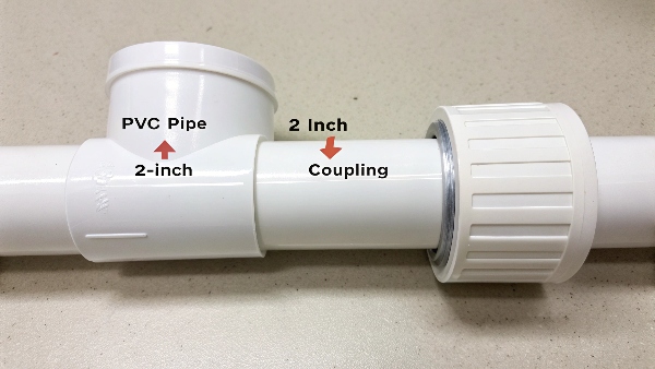 A 2-inch PVC pipe next to a 2-inch coupling, showing the pipe outer diameter is larger than 2 inches