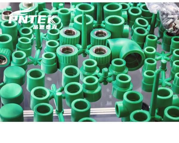 A collection of various white PPR fittings like elbows, tees, and sockets from the Pntek factory