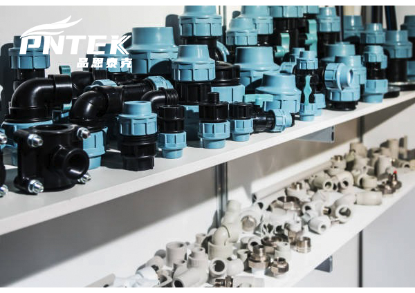 A collection of raw PP pellets next to a finished Pntek fitting