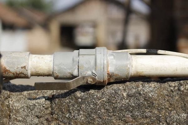 An old, calcified PVC ball valve being cut out of a pipeline
