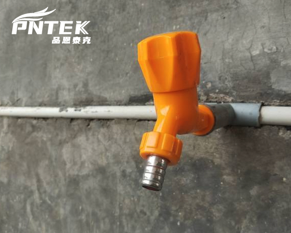 A close-up of a Pntek plastic bib tap mounted on an outdoor wall